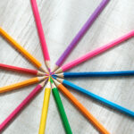 Coloured pencils arranged in a circle on a wooden background